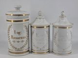 three white and gold canisters with gold trim on them