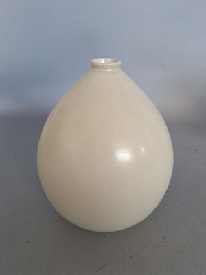 a white vase sitting on a table with a blue background