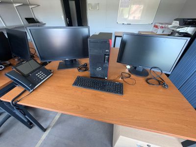 un bureau sur lequel se trouvent trois écrans d'ordinateur et un ordinateur portable