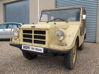 an old yellow jeep parked in front of a garage