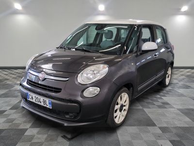 La petite voiture grise est garée dans le garage, sur le sol à carreaux.
