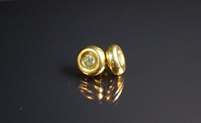 un gros plan sur une paire de boucles d'oreilles en or posées sur une surface noire