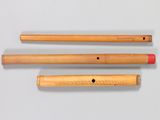 three wooden flutes are lined up on a white surface