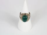 a close up of a ring with a green stone on a white cone