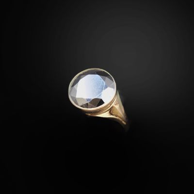 a close up of a gold ring with a faceted diamond