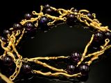 un gros plan d'un bracelet en or orné de perles violettes sur un fond noir
