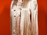 an image of a gold jacket on a mannequin stand against a red wall