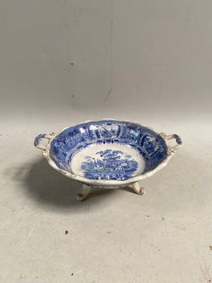 un petit bol bleu et blanc muni d'une anse et posé sur un socle