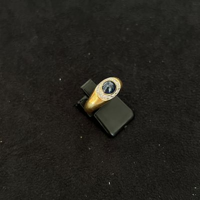 une bague en or sertie d'une pierre bleue posée sur un téléphone portable
