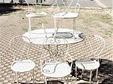 une table et des chaises blanches posées dans une rue pavée