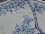 a blue and white plate with a bird and flowers on it