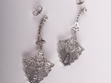 pair of silver earrings with filigree design on them on a white surface