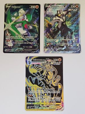 trois cartes à collectionner Pokémon différentes posées sur une surface blanche
