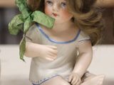 a small doll sitting on a table next to a cup