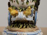a small vase with a bird on top of it on a table