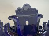 a blue vase with a black handle on a white table