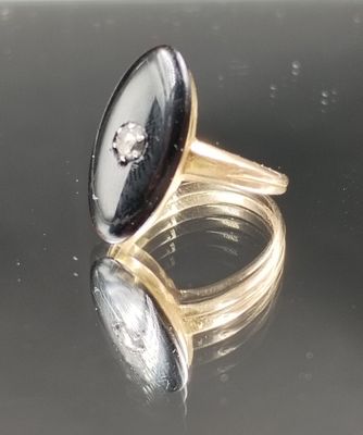 paire de bagues en or ornées de pierres noires et blanches sur une surface réfléchissante