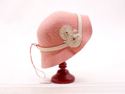 un chapeau rose orné d'une fleur, posé sur un support en bois