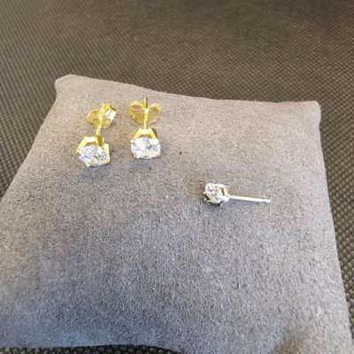 deux paires de boucles d'oreilles en diamant posées sur un coussin