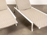 pair of lounge chairs with woven seats in a concrete room