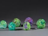 several different colored marbles sitting on top of a gray surface