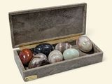 a wooden box with a set of seven marbles in it