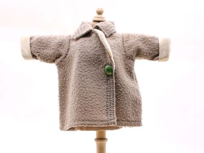 un ours en peluche vêtu d'un manteau, posé sur un mannequin