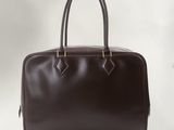 Le sac à main en cuir marron est posé sur une surface blanche.
