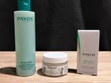 un flacon de Payot et une boîte de crème posés sur une table