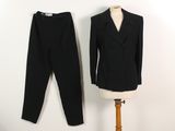 un costume noir et un pantalon posés sur un support à côté d'un mannequin