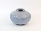 un vase bleu posé sur une surface blanche