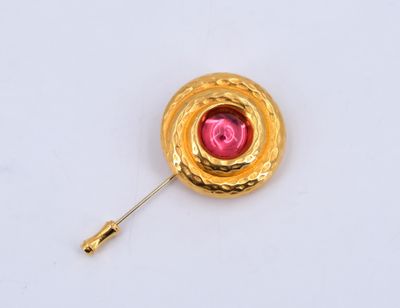 une image représentant une broche en or ornée d'une pierre rose au centre