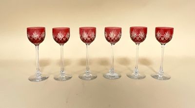 six verres à vin rouge alignés en rang sur une table