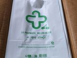 un sac blanc orné d'un logo vert, posé dans une boîte