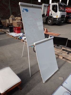 un tableau blanc posé par terre à côté d'une chaise blanche