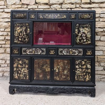 une armoire noire et dorée avec une porte en verre rouge