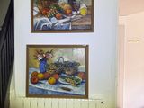 deux tableaux accrochés au mur au-dessus d'une table sur laquelle sont disposés des fruits