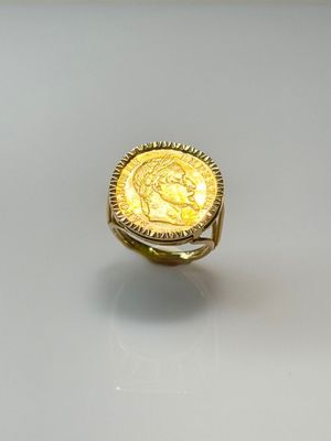 a close up of a gold ring with a coin on it