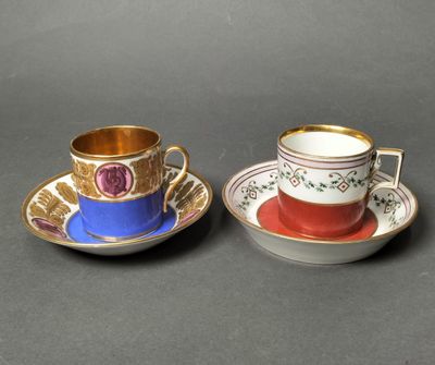 two cups and saucers with gold rims on a black surface