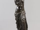 a bronze statue of a woman holding a baby on a clear base