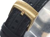 a close up of a black watch with a gold buckle