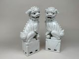 une paire de figurines blanches « foo foo foo » posées sur une boîte