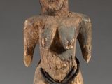 a close up of a wooden statue on a stand with a gray background