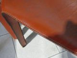 a close up of a brown leather chair on a tile floor