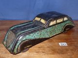 une vieille petite voiture jouet verte et noire posée sur une table en bois