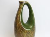 a green vase that is sitting on a white surface