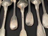six silver spoons with monograms on them sitting on a black surface