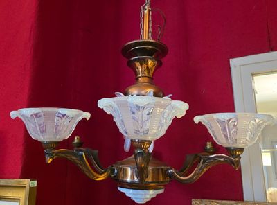 un lustre auquel sont suspendus trois abat-jours en verre