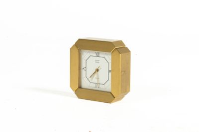 a small gold clock sitting on a white surface