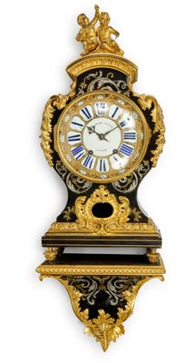 une image représentant une horloge noire et dorée accrochée à un mur blanc